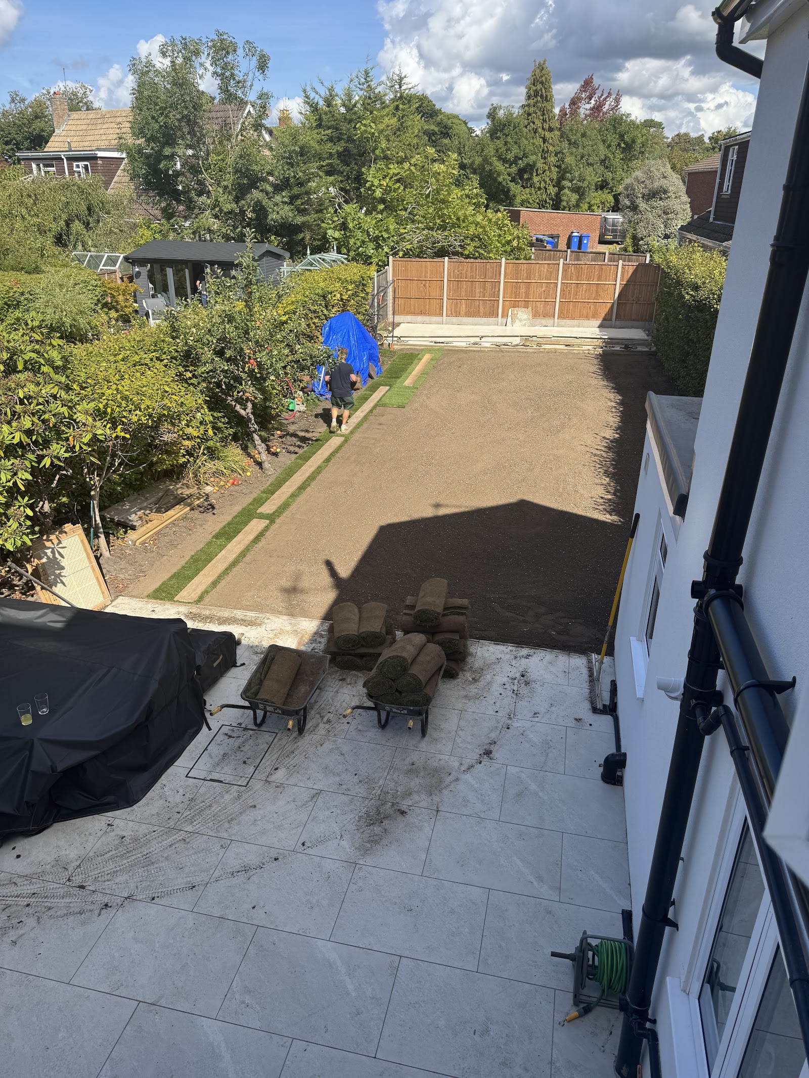 The stage that matters most: a large garden stripped, levelled and graded, topsoil base prepared, with fresh turf rolls stacked and ready to lay.